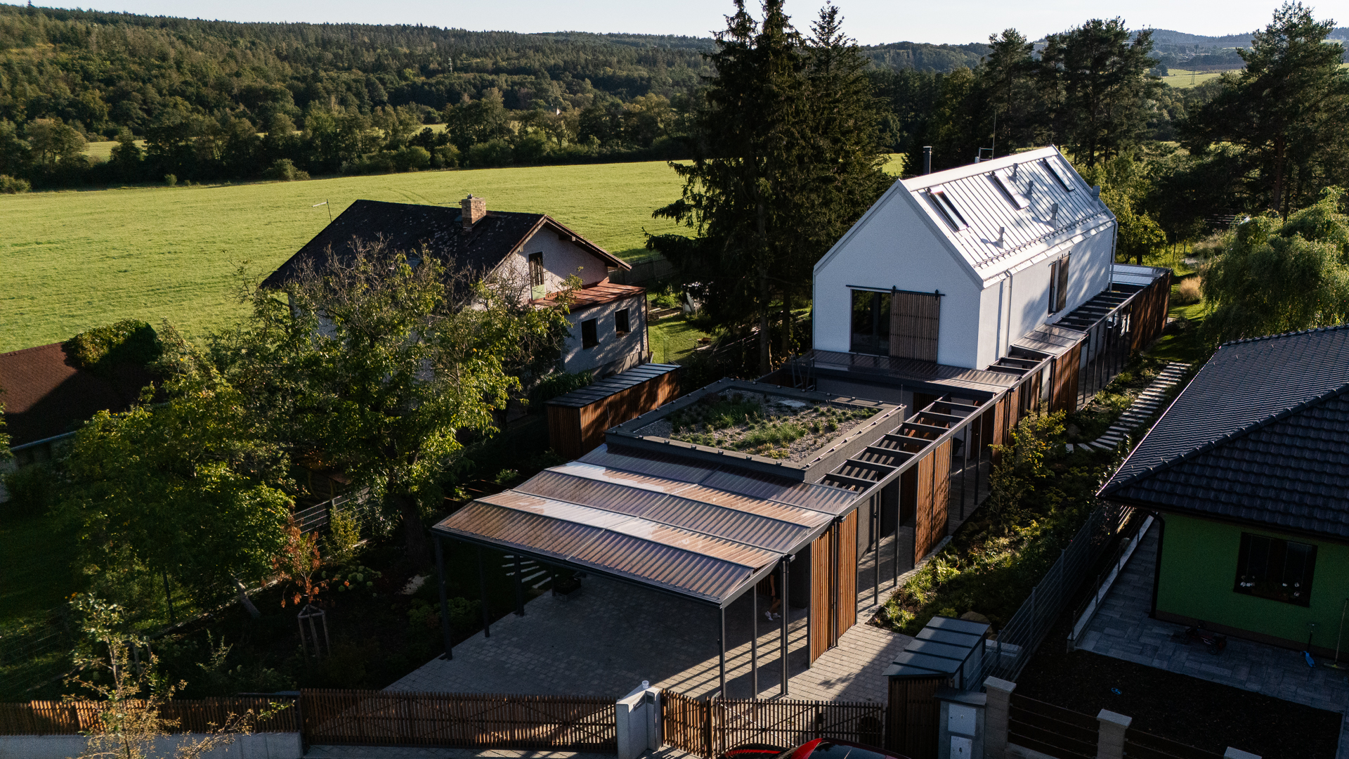 Timber house with white facade and carport on a narrow plot between neighbouring houses